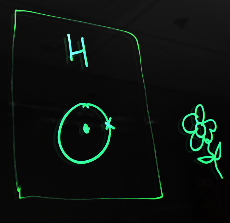 Drawing of a hydrogen Bohr model and a flower on a light board.