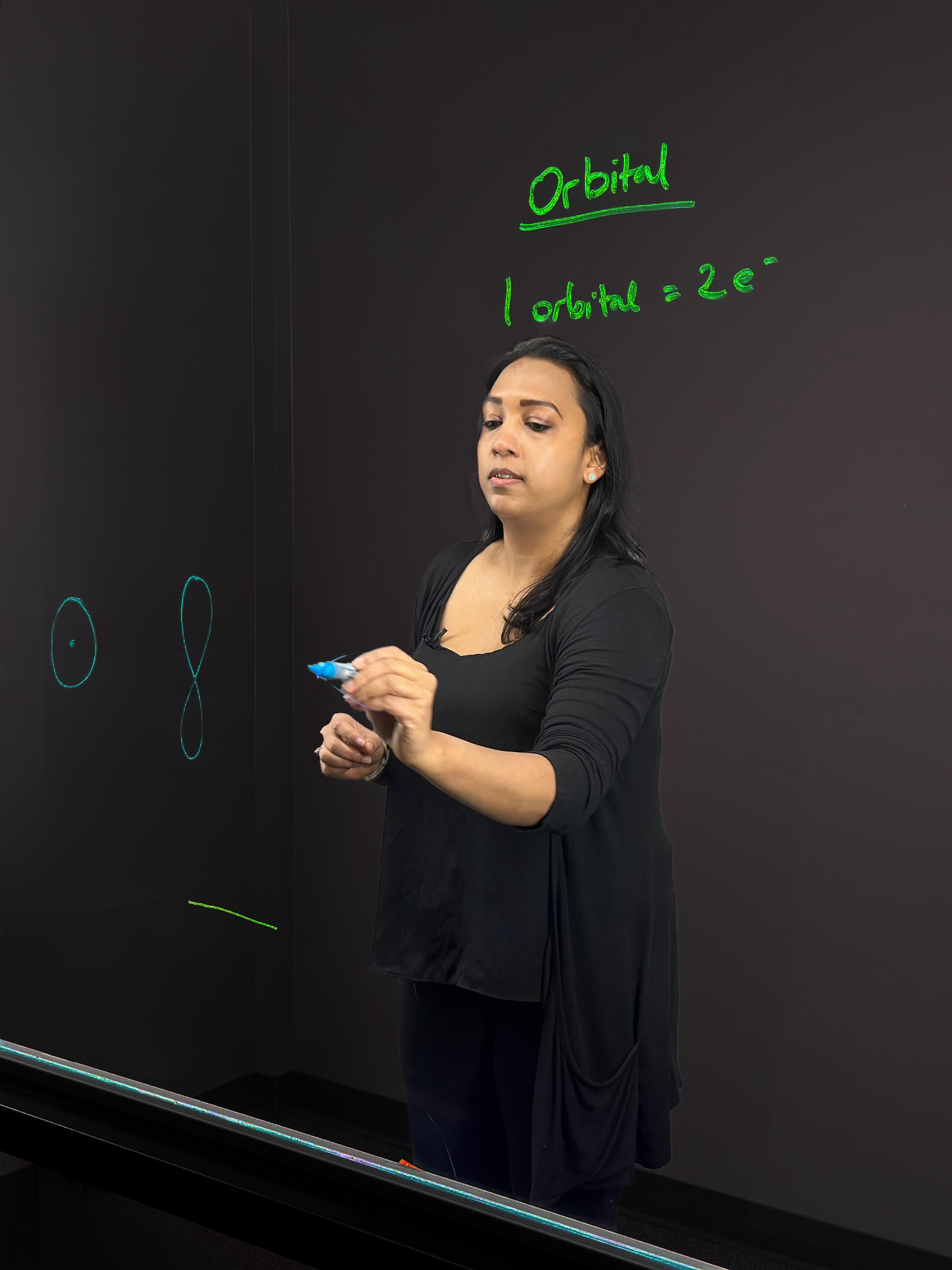 Professor writing on light board to explain orbitals in the Bohr model.